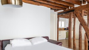 Un dormitorio con cama, vigas de madera y vistas a una zona de cocina.