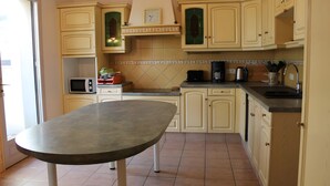 Une cuisine avec des meubles de couleur beige, un four à micro-ondes, une machine à café et une table.