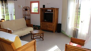 Un salon comprenant un canapé, un meuble en bois, une télévision et une petite table.