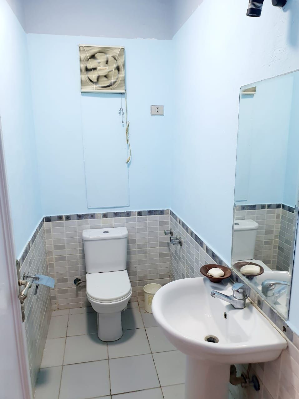 Ein Badezimmer mit Toilette, Waschbecken und Spiegel.