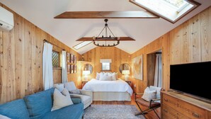 Un dormitorio con una cama grande, un sofá azul, un aparador de madera y un televisor.