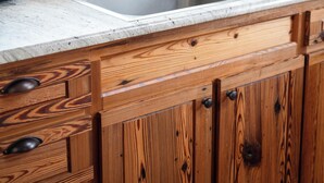 Una cocina con armarios de madera, un lavamanos de acero inoxidable y una ventana con vistas a árboles.