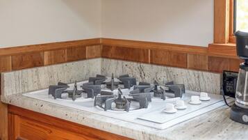 A kitchen with a built-in microwave, gas stove, wooden cabinets, and a marble countertop.