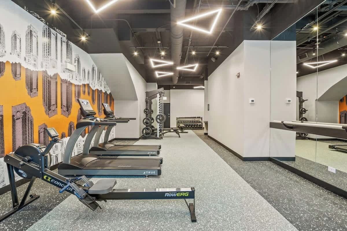 A gym with treadmills, weight machines, and a mirrored wall.