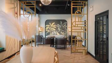 Een moderne hotelkamer met een eethoek, een groot raam en een decoratief kunstwerk.