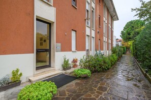 A building with a stone pathway, a door, and potted plants.