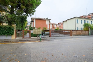 A residential street with houses, a bicycle, and a gated entrance.