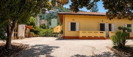 A building with a yellow facade, a tiled roof, and a paved courtyard.