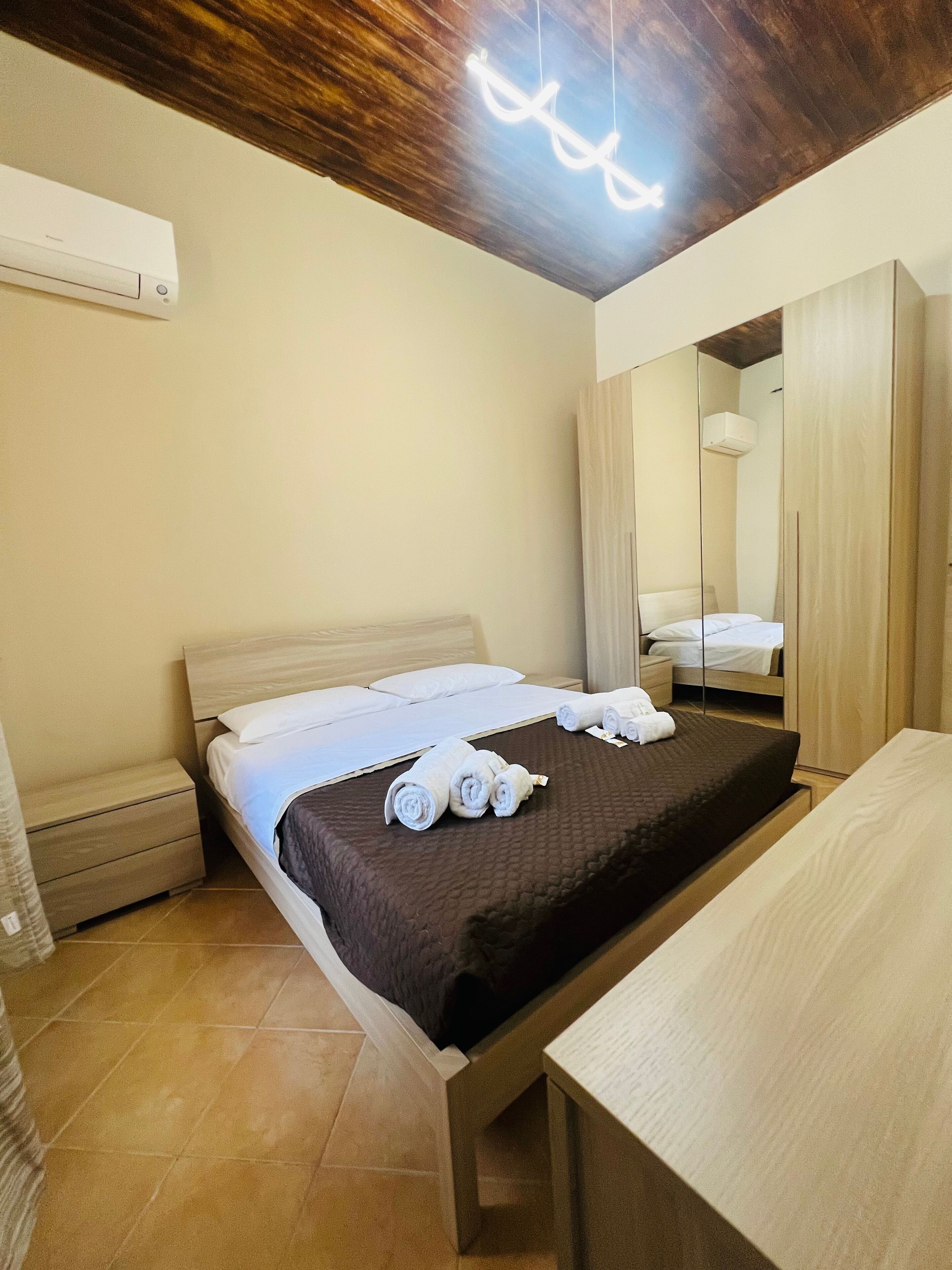 Ein Hotelzimmer mit einem Bett, einem Nachttisch, einem Spiegel und einer Deckenleuchte.