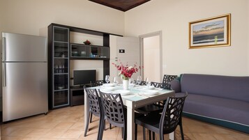 Un espacio habitable compacto con comedor, kitchenette y sofá.