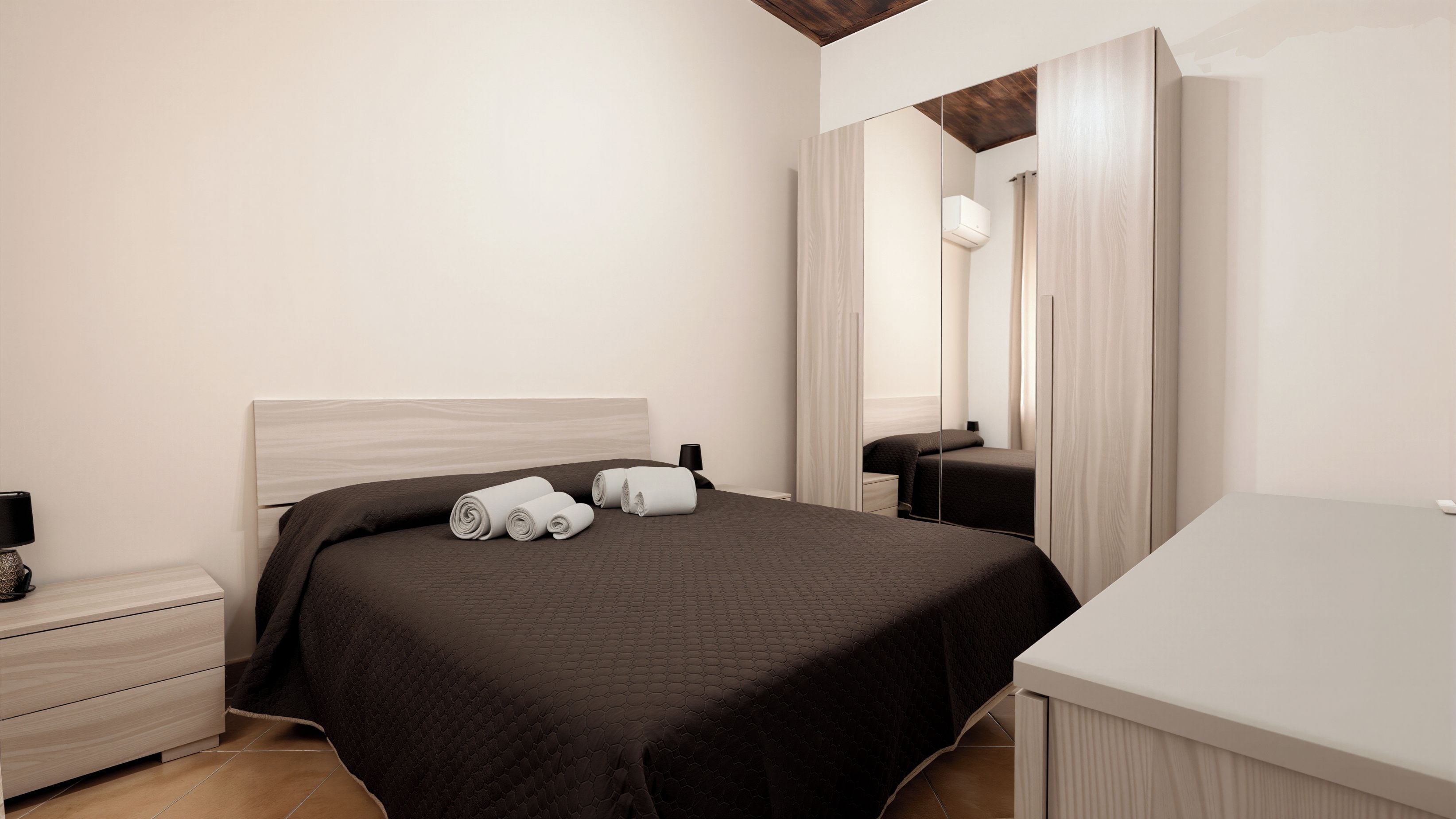 Una habitación de hotel con una cama, una mesita de noche, un espejo y una pequeña mesa.