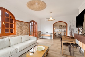 A spacious living area with a sofa, dining table, and kitchen in the background.