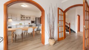 A modern kitchen with white cabinets, a wooden dining table, and chairs. There is a potted plant in the center. - 'Roque Bentayga' with Mountain Views, Wi-Fi, and Air Conditioning (Las Palmas)