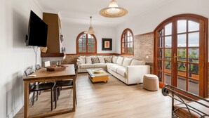 A modern living room with a wooden dining table, a sofa, and a television. - 'Roque Bentayga' with Mountain Views, Wi-Fi, and Air Conditioning (Las Palmas)