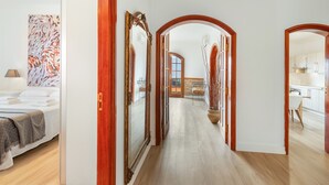 A hallway with wooden flooring, a bed with a white headboard, and a large mirror. - 'Roque Bentayga' with Mountain Views, Wi-Fi, and Air Conditioning (Las Palmas)