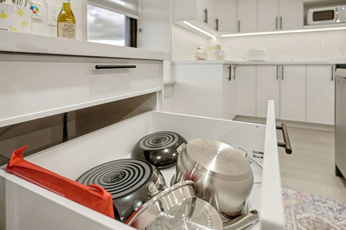 A modern kitchen with white cabinets, a microwave, and a stainless steel range hood.