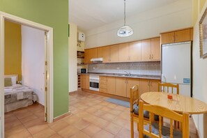 Una cocina compacta con armarios de madera, un refrigerador blanco y una mesa de comedor con sillas.
