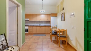 A kitchen with wooden cabinets, a dining table with chairs, a refrigerator, and a hanging light fixture. - Vacation Apartment 'Guía' with Shared Terrace, Shared Garden and Wi-Fi (Tejeda)