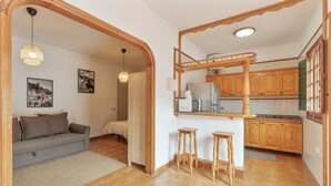 A compact living space with a kitchenette, a sofa, a dining area, and a staircase leading to an upper level.