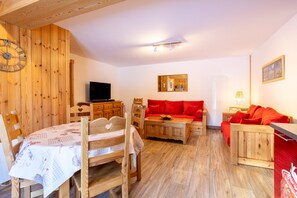 Ein Holzinterieur mit einem Esstisch, Stühlen, einer Couch und einem Fernseher.