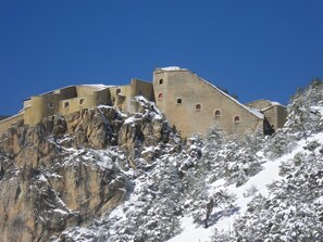 Ein historisches Steinhaus mit vielen Fenstern und einer verschneiten Landschaft.