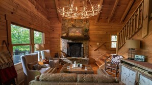Interior acogedor de una cabaña con chimenea de piedra, paredes de madera y una zona de estar confortable.