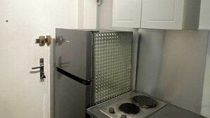 Eine kleine Küche mit Kühlschrank, einer Arbeitsplatte und Küchenschränken darüber.