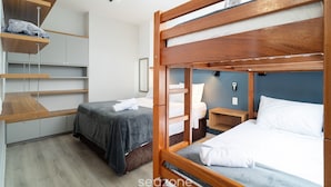 Ein Zimmer mit zwei Betten, Holz-Kopfteilen und eingebauten Regalen.