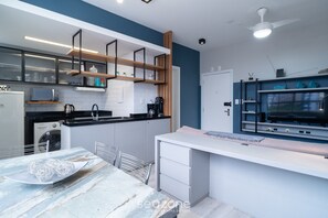A modern kitchen with white cabinets, a built-in microwave, and a coffee machine.