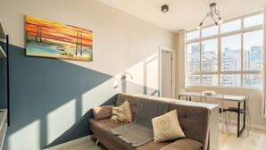 Ein modernes Wohnzimmer mit einer Couch, einem Gemälde einer Brücke und einem Essbereich mit Tisch und Stühlen.