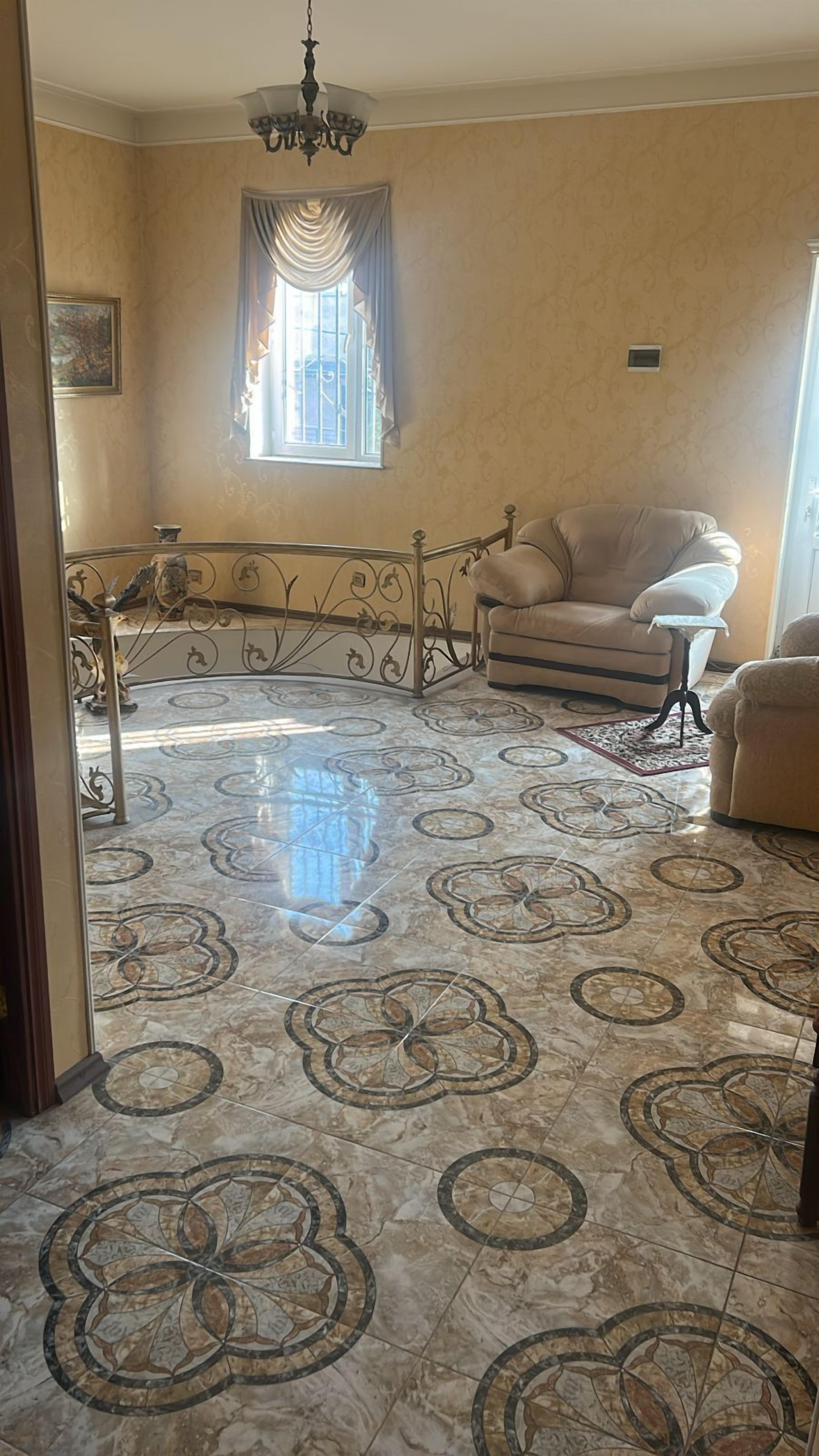 A room with a patterned floor, a sofa, a small table, and a window with curtains.