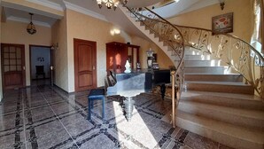 A grand foyer with a marble floor, a staircase with ornate metal railings, and a chandelier. - Avan Luxury Villa (Arinj)