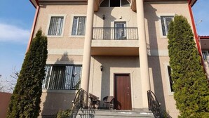 A two-story building with a balcony, a wooden door, and a small outdoor seating area. - Avan Luxury Villa (Arinj)