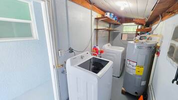 A laundry room with a front-loading washer, a stacked washer and dryer, and a water heater.