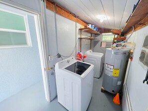 A laundry room with a front-loading washer, a stacked washer and dryer, and a water heater. - Cozy 3br 2ba Winter Haven Getaway Chain of Lakes (Winter Haven)