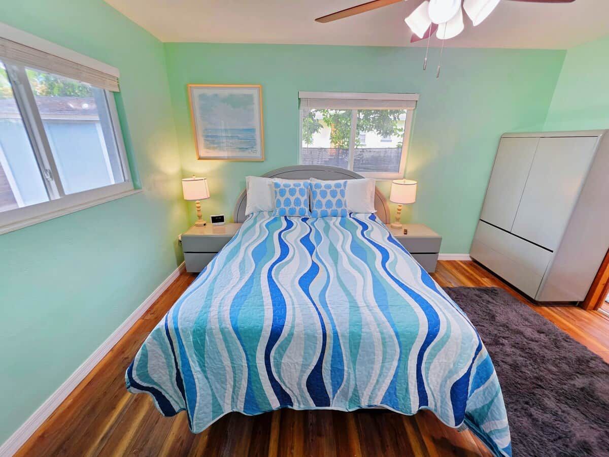 Une chambre à coucher comprenant un lit, deux tables de chevet, une commode, une coiffeuse et un ventilateur de plafond.