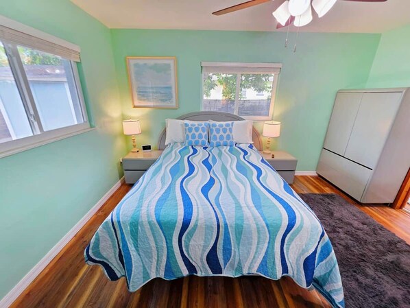 A bedroom with a bed, two bedside tables, a nightstand, a dresser, and a ceiling fan.