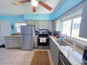 A kitchen with a refrigerator, stove, oven, and a window with a view.