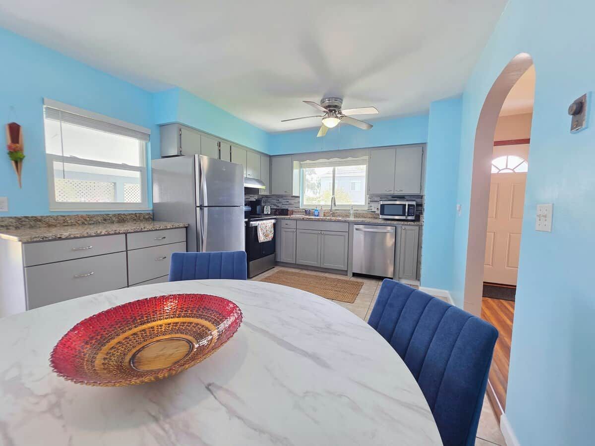 A kitchen with a dining table, chairs, and a ceiling fan.