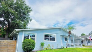A light blue single-story house with a front porch, a small lawn, and a palm tree. - Cozy 3br 2ba Winter Haven Getaway Chain of Lakes Downtown (Winter Haven)