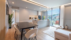 A modern kitchen with a central island, white cabinetry, and a large window offering a city view. - Orion Calheta Hills by LovelyStay (Calheta)