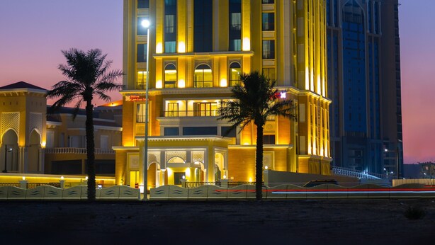Un hotel alto con un cartello ben visibile 'Hilton Garden Inn', diversi piani e una facciata ben illuminata.