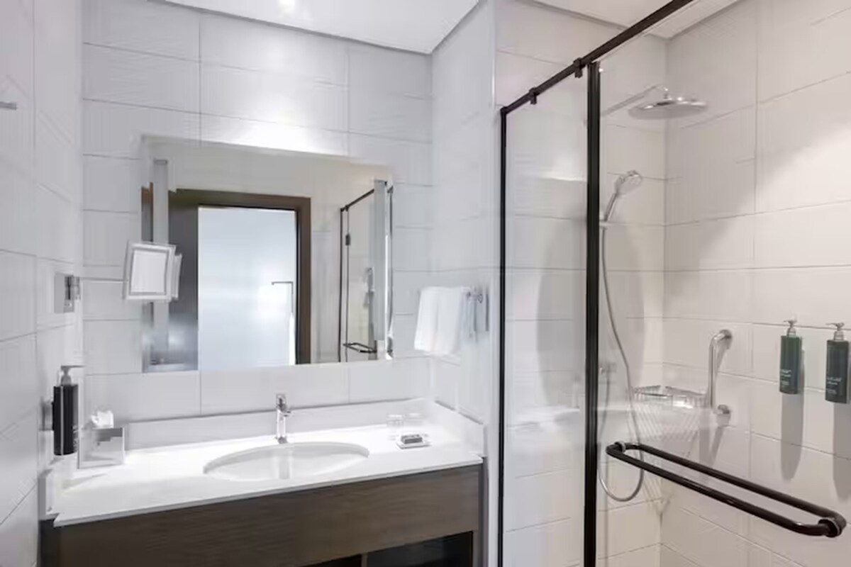 Un baño moderno con cabina de ducha de vidrio, tocador doble y un espejo grande.