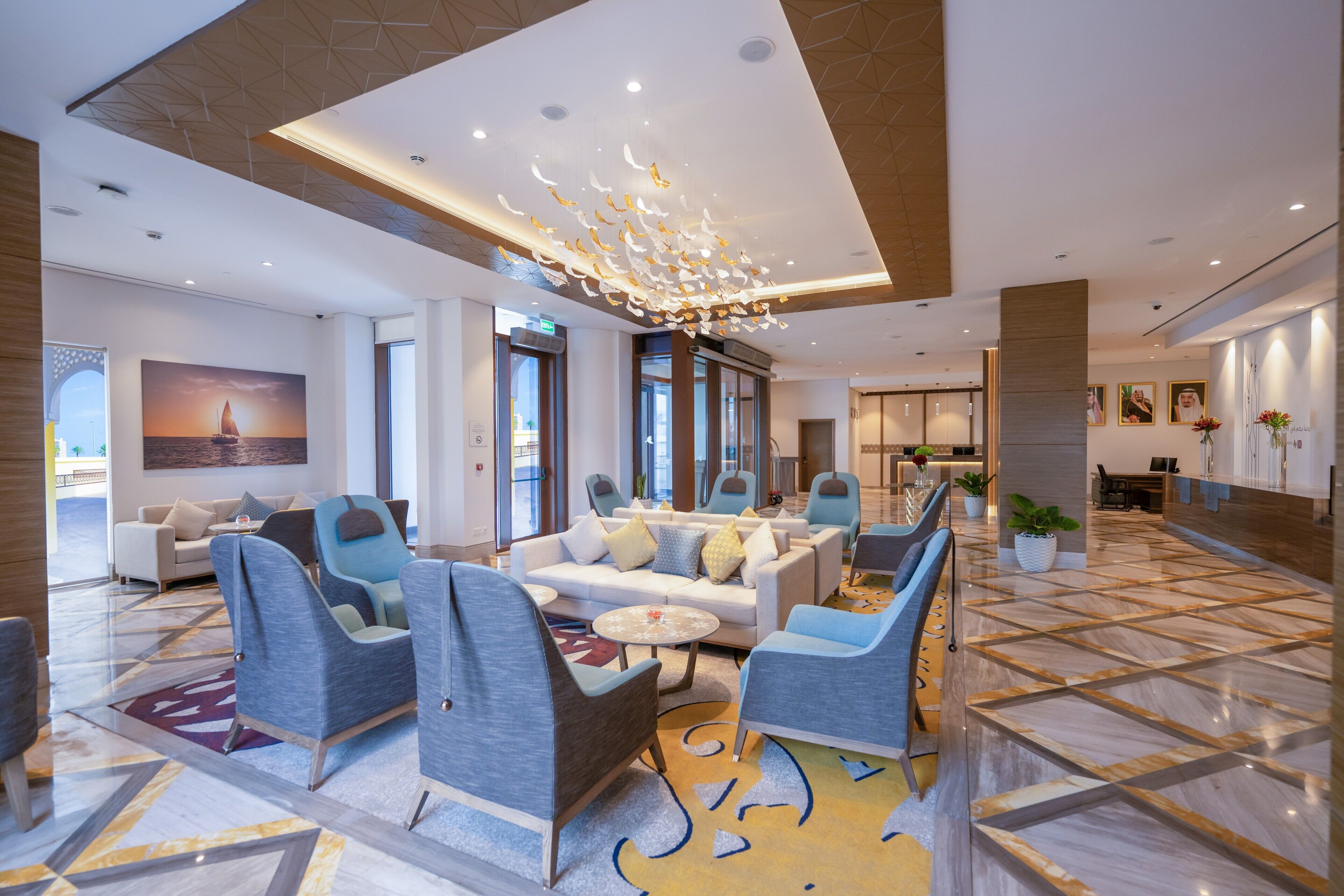 A spacious lobby with modern seating, a large painting, and a patterned floor.