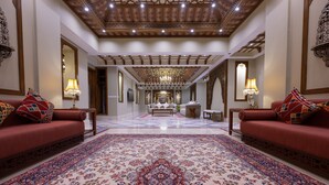 Un'ampia hall con un tappeto decorativo di grandi dimensioni, divani rossi e un lampadario.