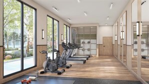 Una palestra con attrezzature per esercizi, ampie finestre e vista su spazi verdi.