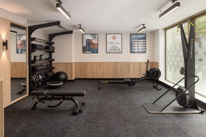 Une salle de sport équipée de matériel d’exercice, d’un banc et ornée d’affiches motivantes sur les murs.