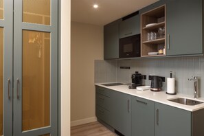 A kitchen with grey cabinets, a microwave, a coffee maker, and a sink. - Home2 Suites By Hilton Dublin City Centre (Dublin)
