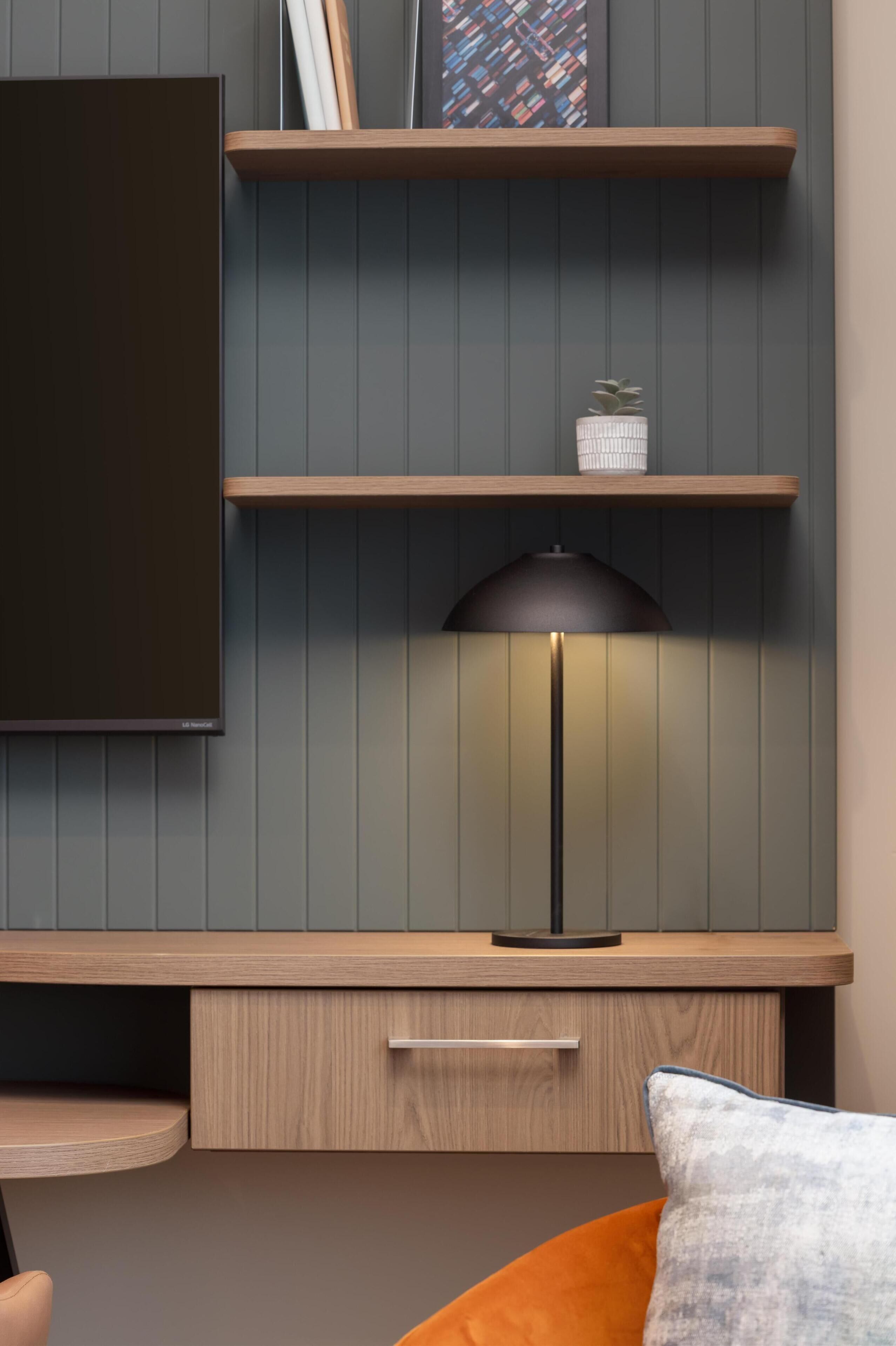Una sala de estar moderna con televisor de pantalla plana, estanterías de madera, una lámpara y un sofá.