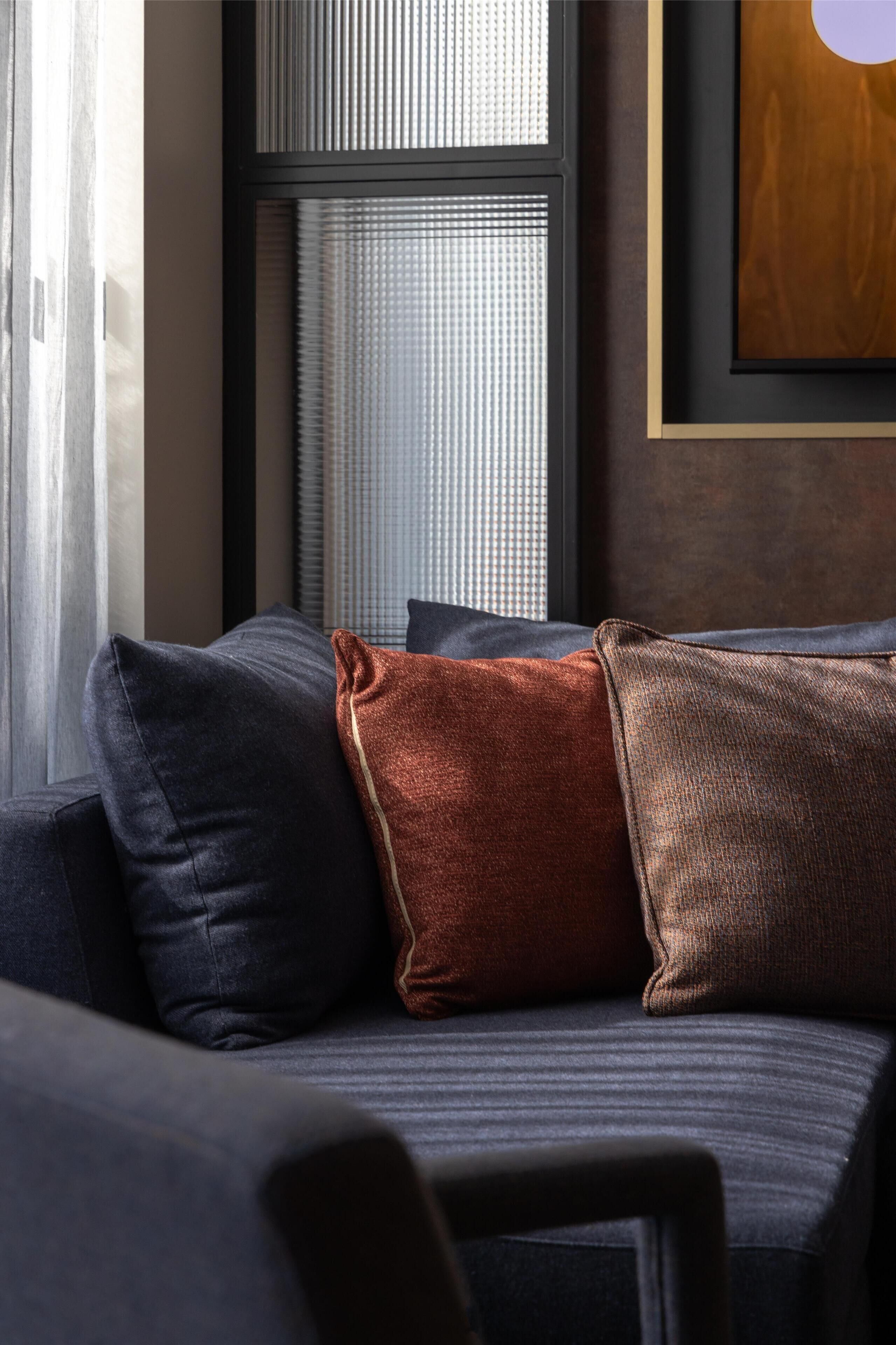 A modern living room with a sofa, a window with blinds, and a framed picture on the wall.